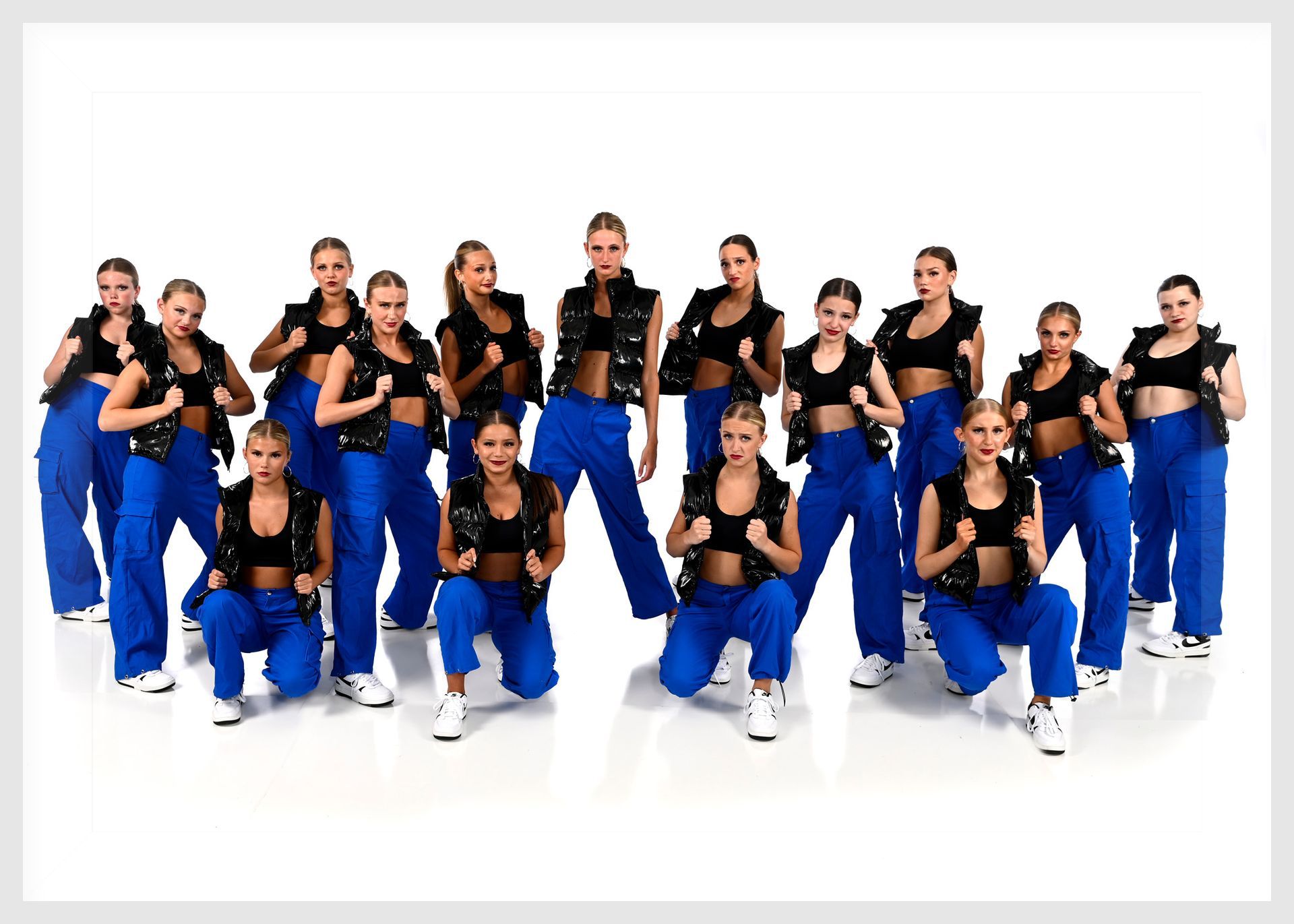 A group of young women in black leotards are posing for a picture.
