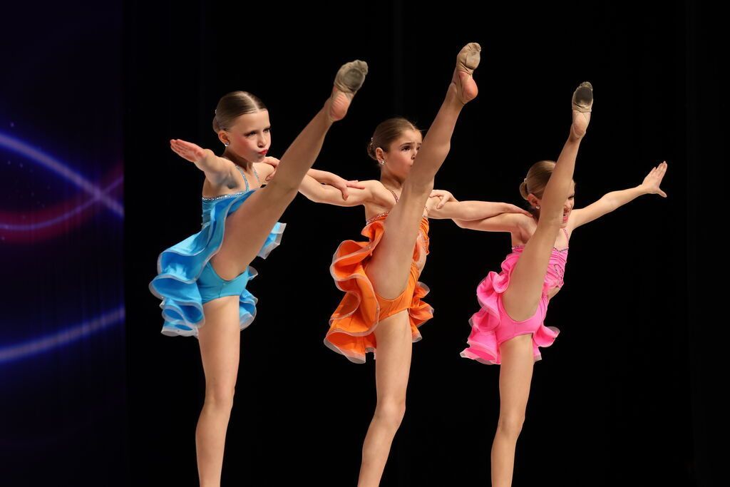 A group of dancers are performing in front of a sign that says legacy