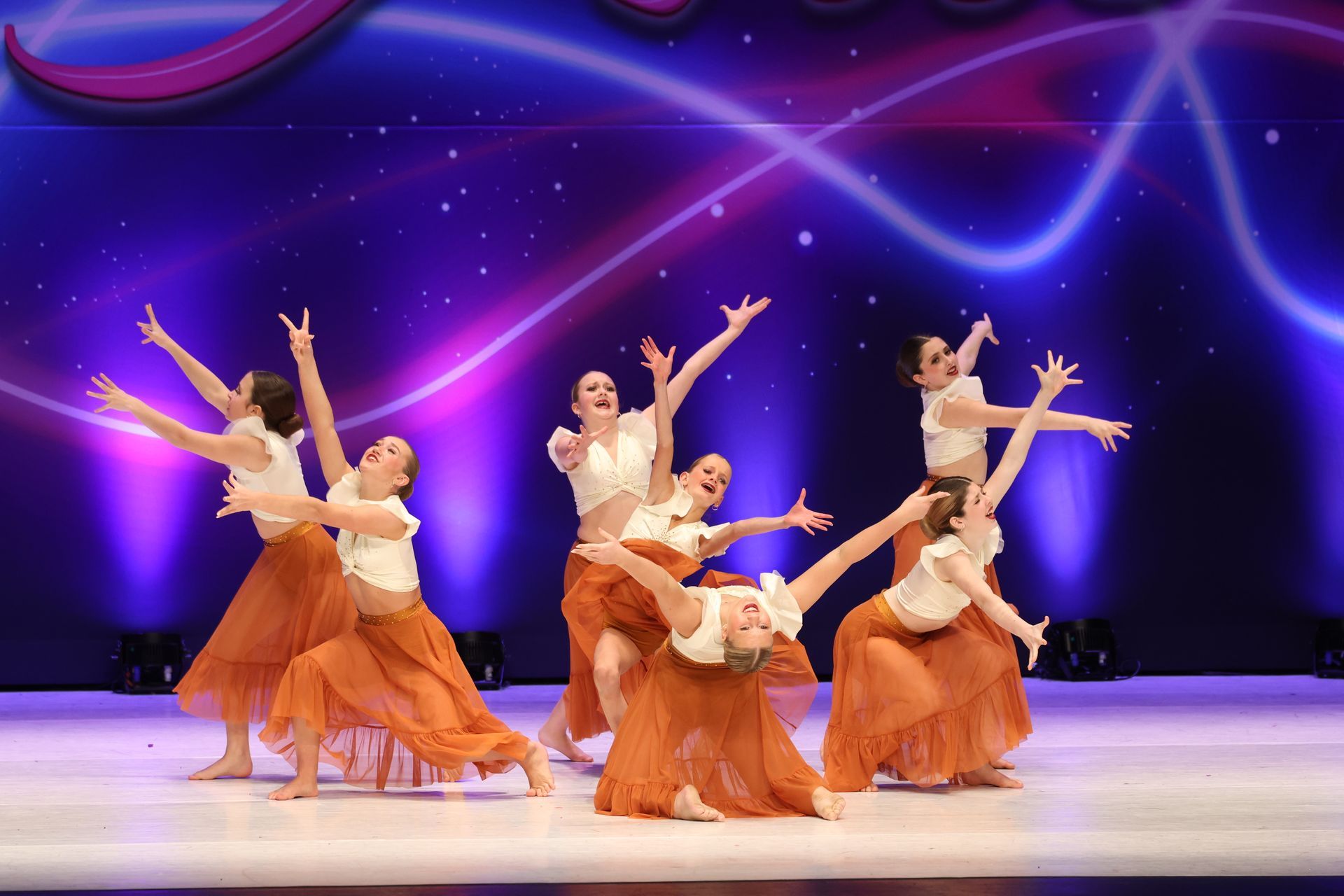 A group of dancers are performing on a stage in front of a sign that says legacy national dance competition.