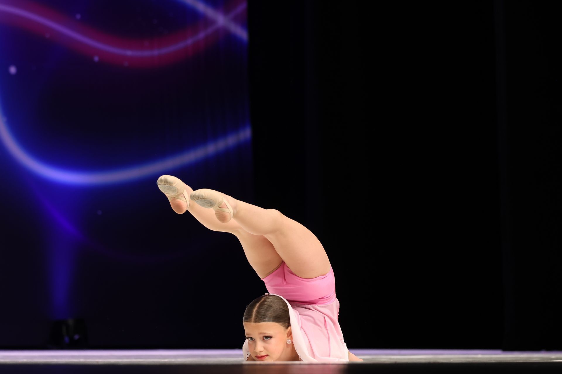 A woman is doing a handstand in front of a sign that says national dance com