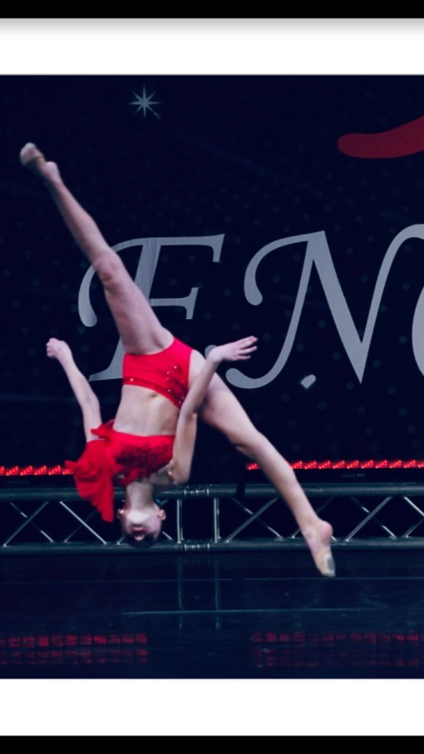 A female gymnast is doing a handstand on a stage