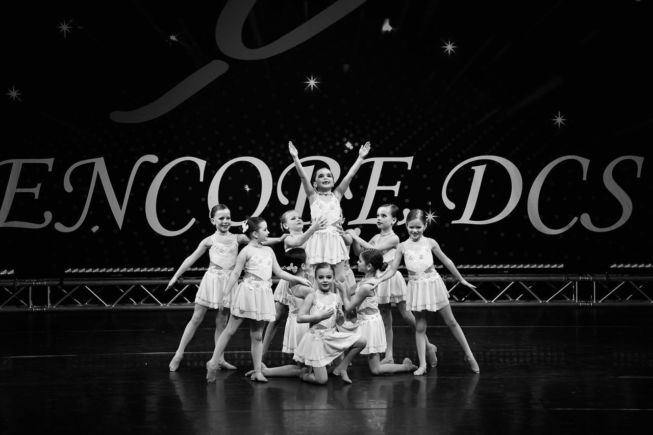 A female gymnast is doing a split on a white background.