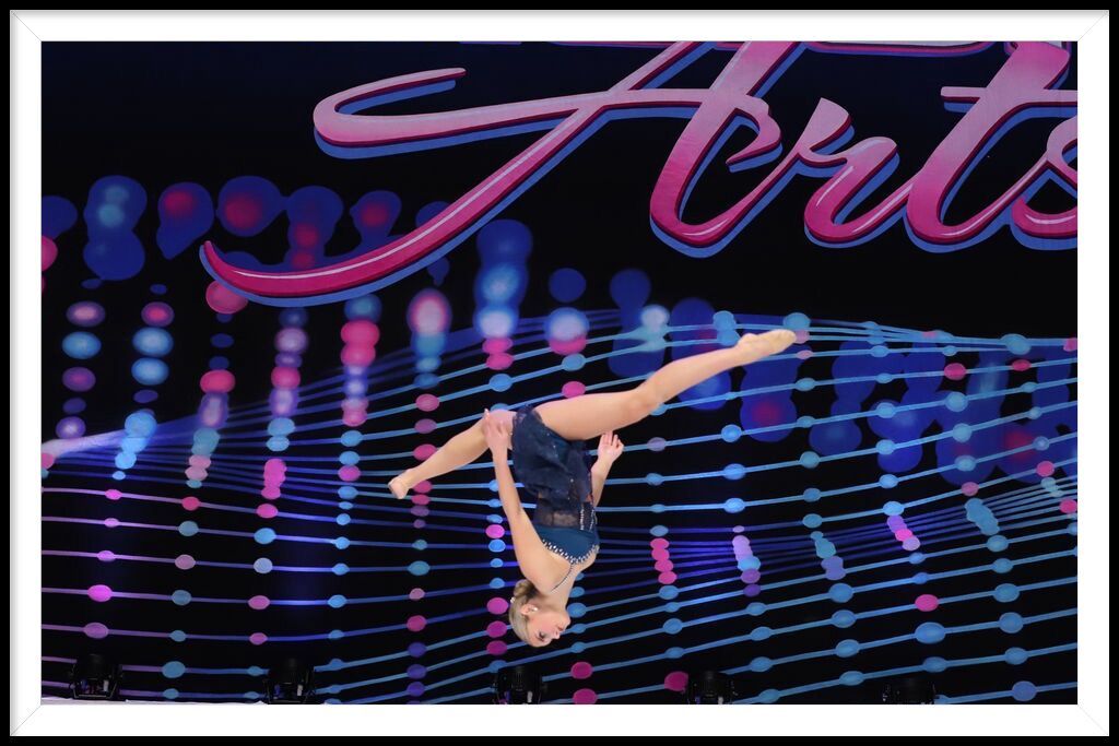 A woman is doing a handstand in front of a sign that says competition