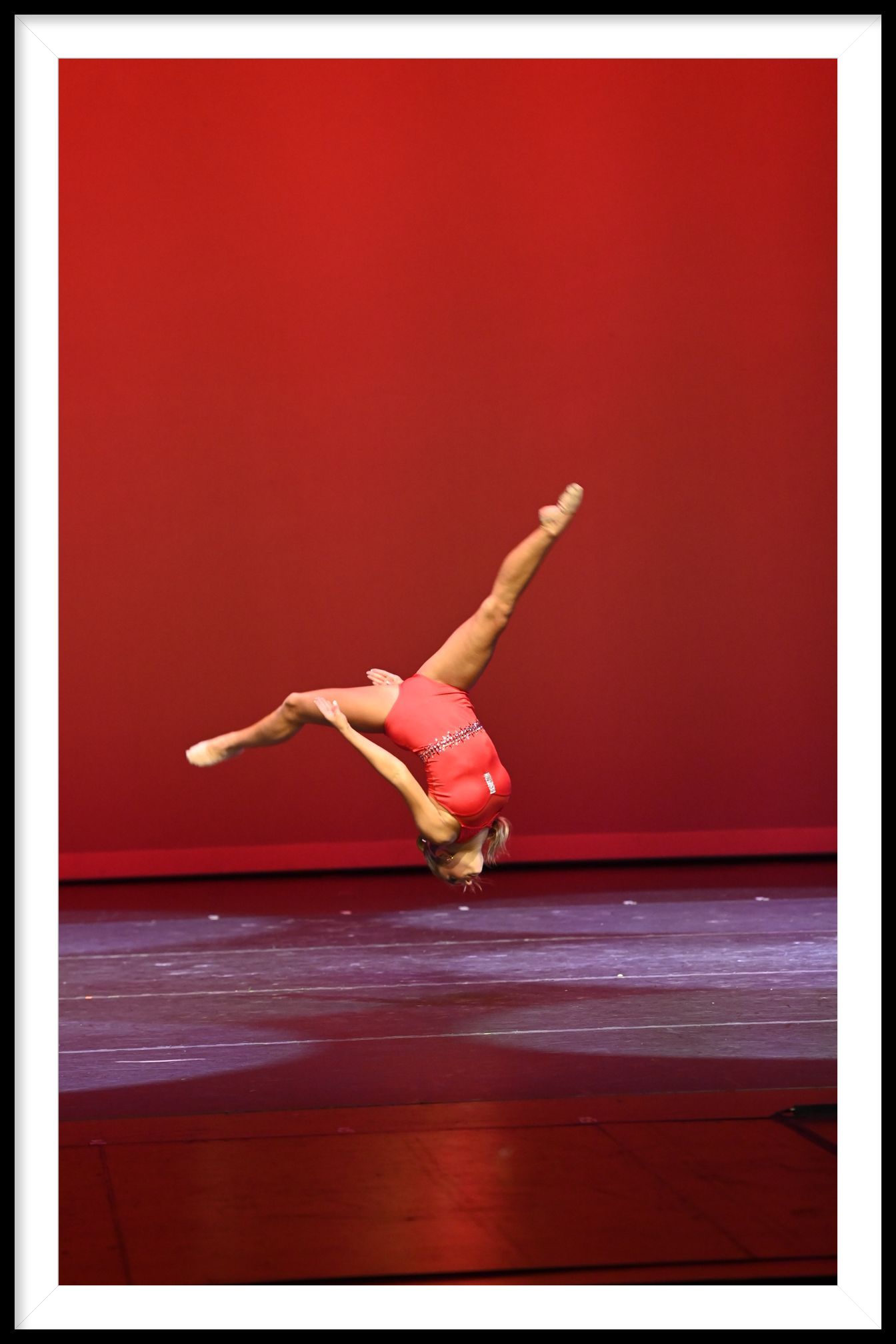 A gymnast is doing a handstand on a red background