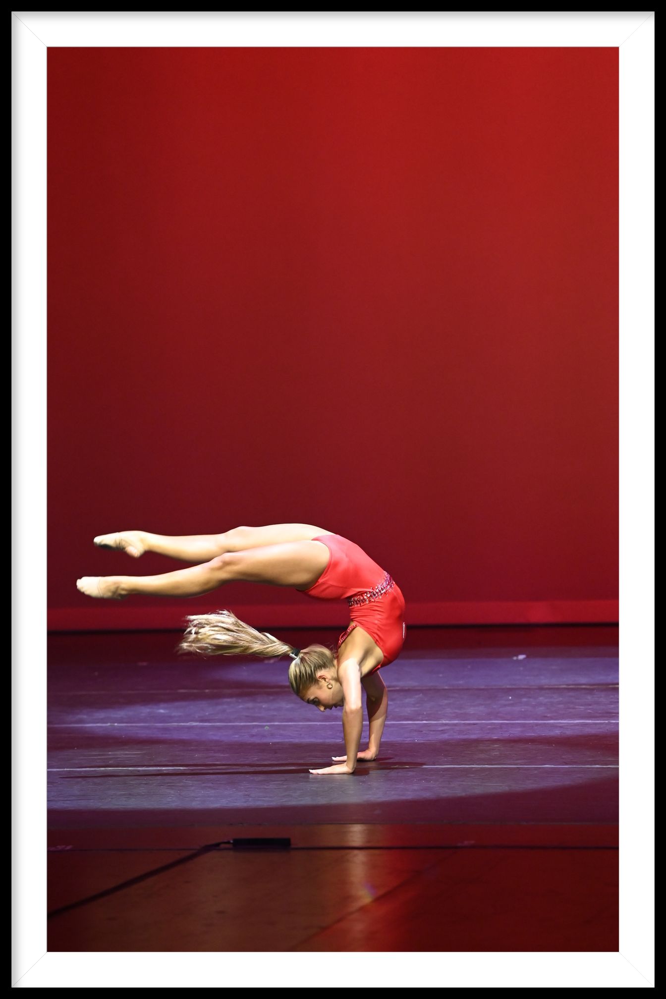 A woman is doing a handstand in front of a sign that says national dance