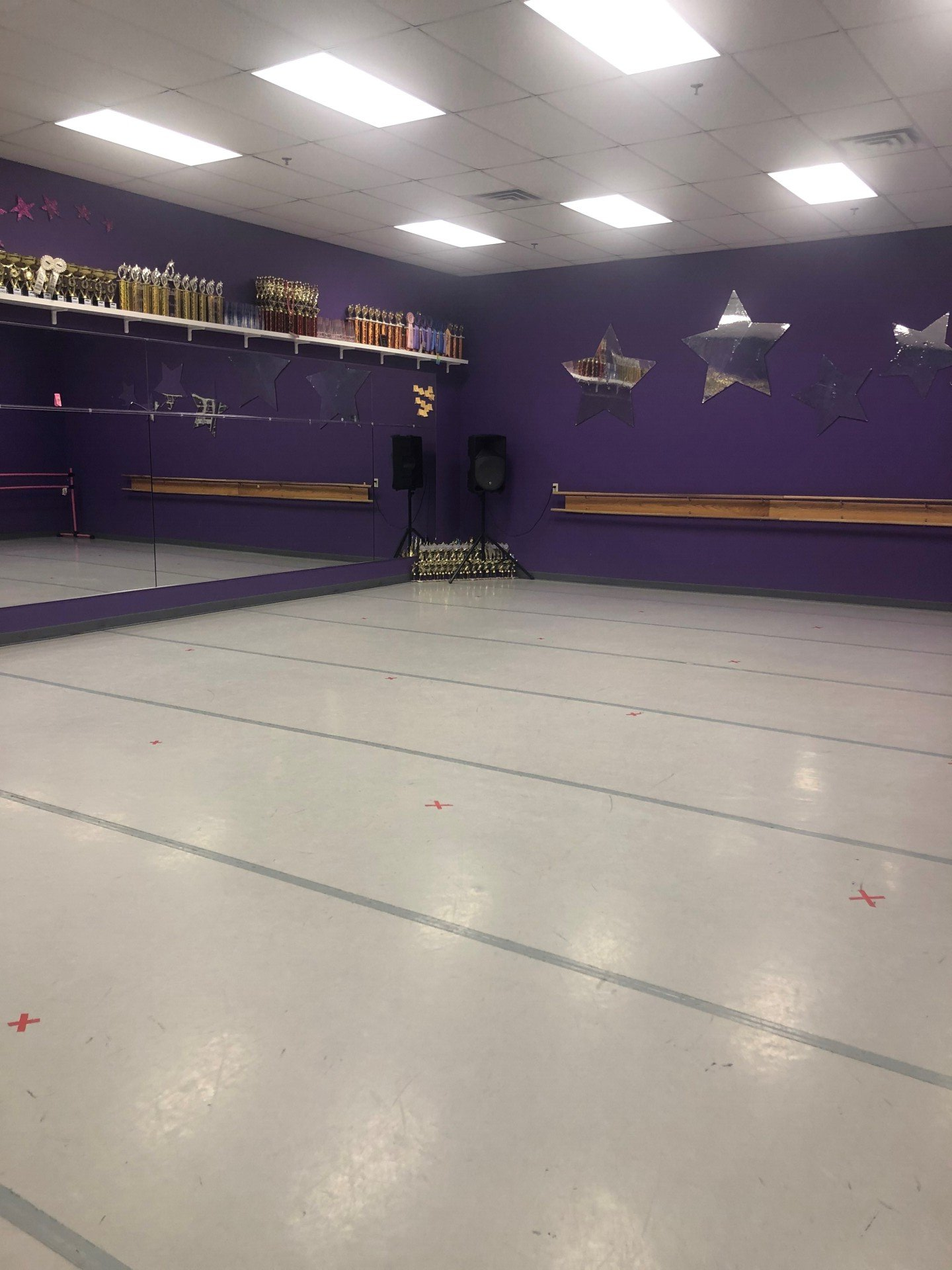 An empty dance studio with purple walls and a large mirror