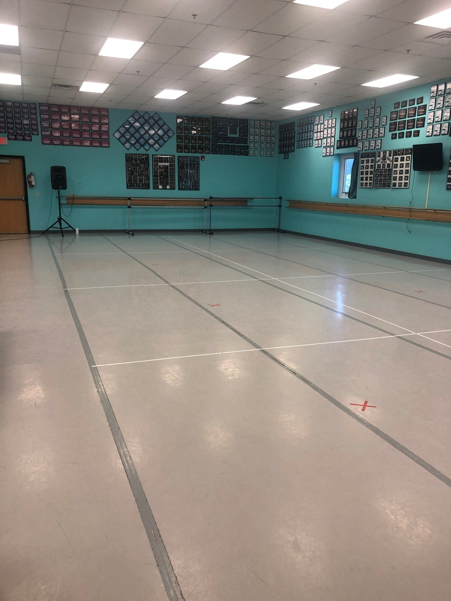 A large empty dance studio with a gray floor and blue walls.
