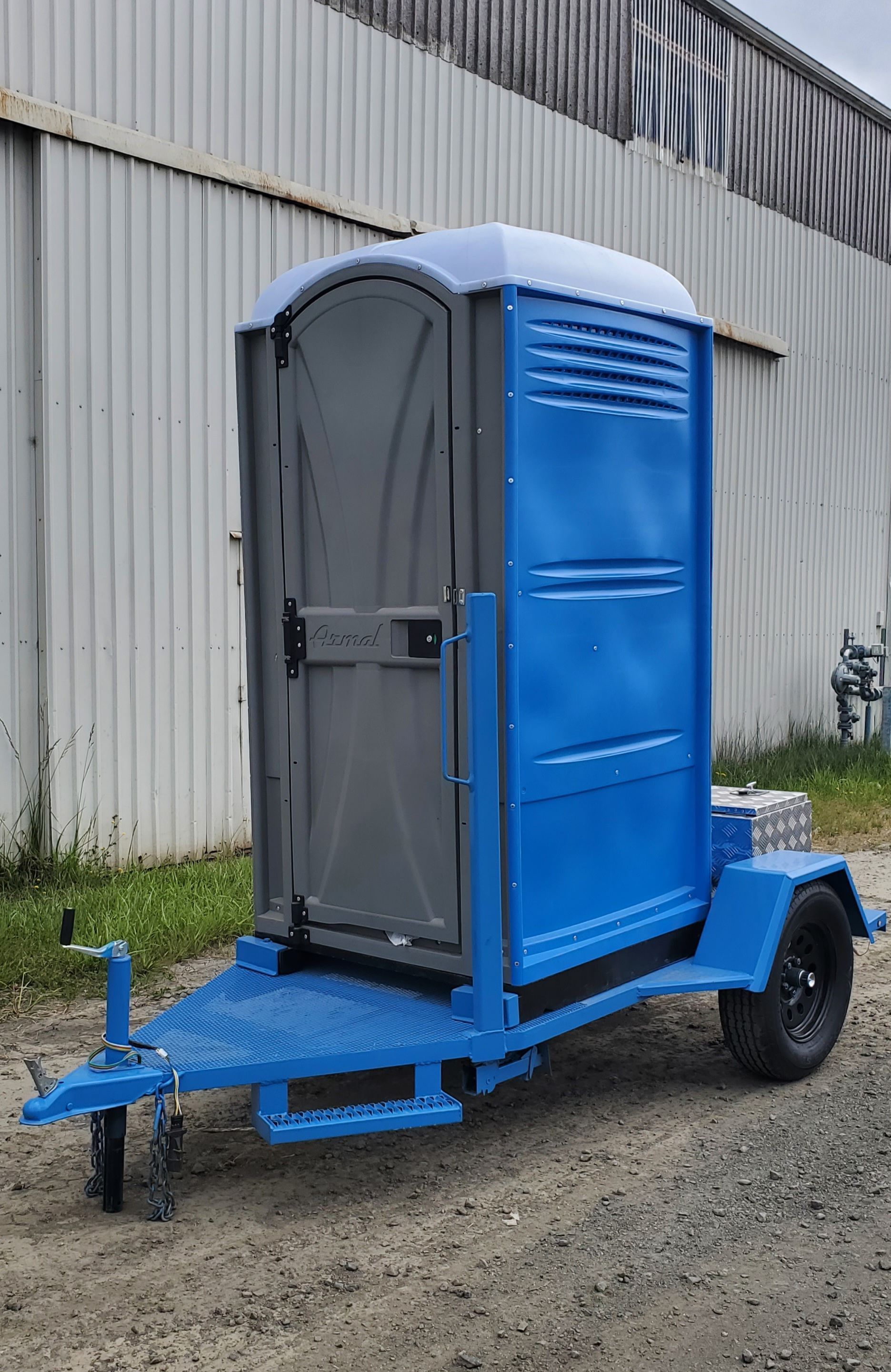 A blue portable toilet is on a trailer.