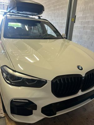 White BMW SUV with black grille and roof cargo box.