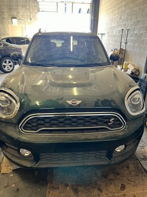 Green Mini Cooper SUV in a garage, facing forward.