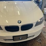 White BMW car front with black grill, logo, and license plate.
