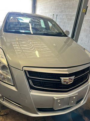Silver Cadillac sedan parked in a garage, front view.
