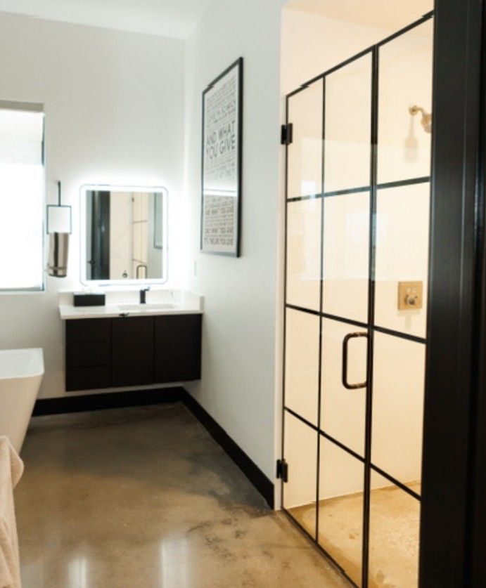 Modern bathroom with glass shower door, black vanity, wall mirror, and white walls