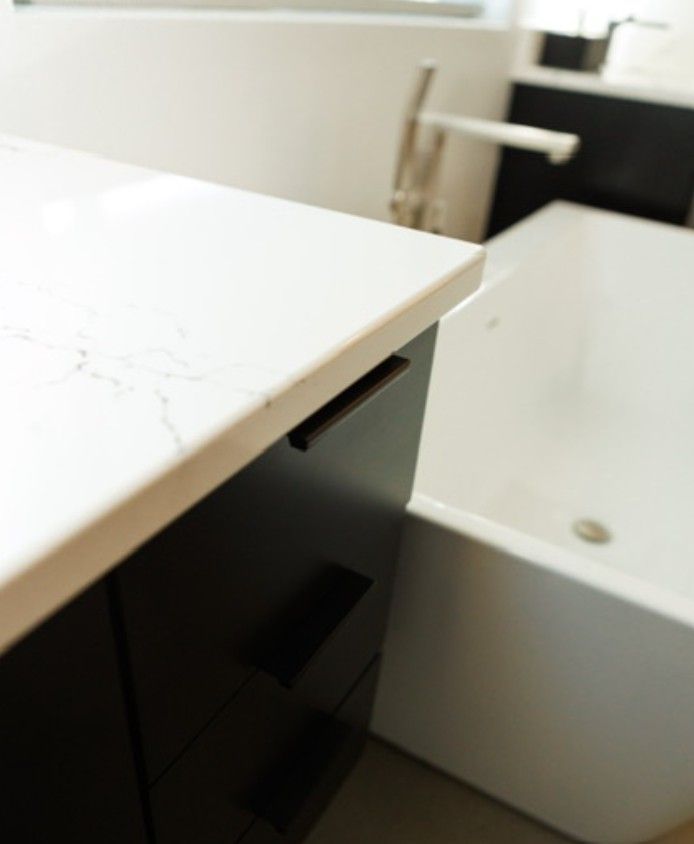 Modern bathroom with a white vanity countertop and a bathtub in the background