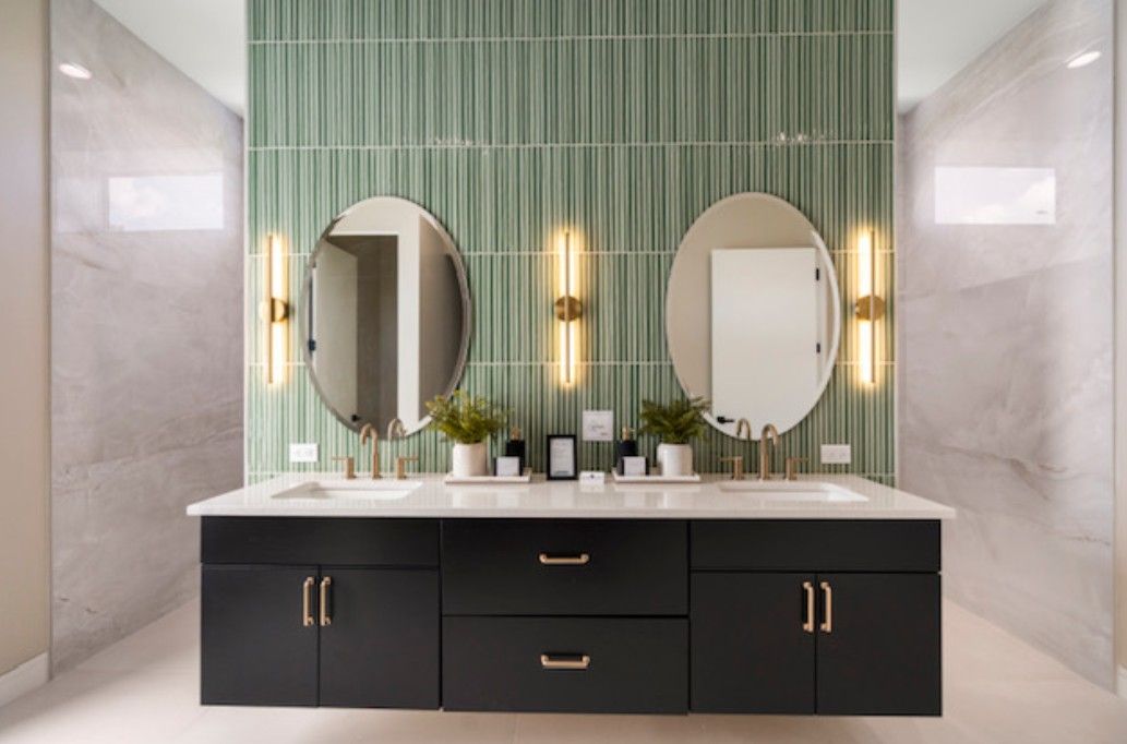 Modern bathroom vanity with twin oval mirrors, black cabinets, and green tiled accent wall