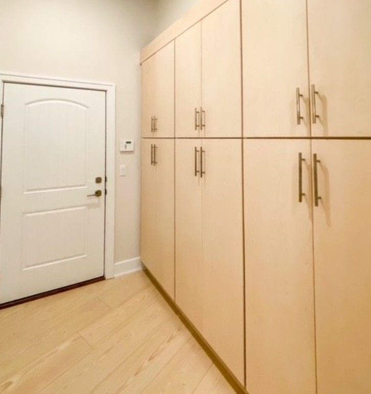 Small hallway with a white door and light wood built-in cabinets along the wall.