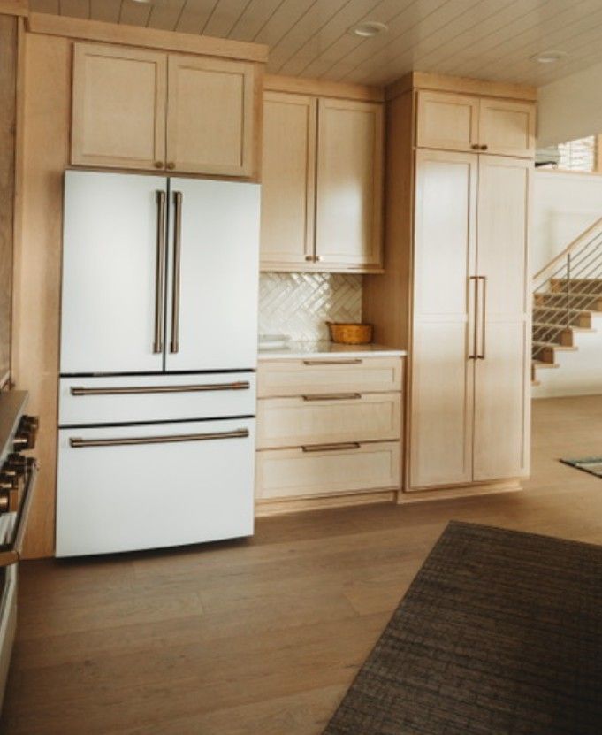 Modern kitchen with light wood cabinets, white refrigerator, and hardwood floor.
