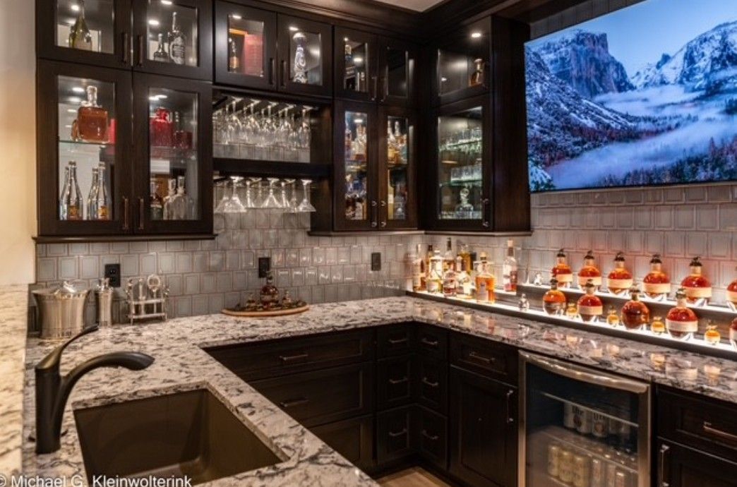 Elegant dark-wood home bar with glass cabinets, marble counter, wine display, and wall art