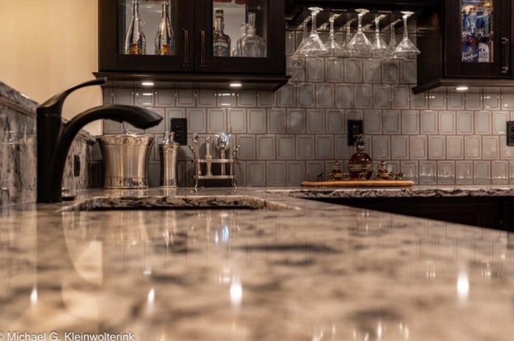 Modern kitchen with a marble countertop, black faucet, and glassware against a tiled backsplash