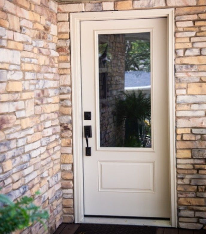 Cream-colored front door with glass panel, set in a stone entryway.