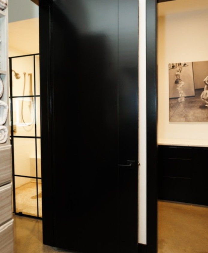 Black doorway in a gallery hallway with framed photos and warm lighting on the walls