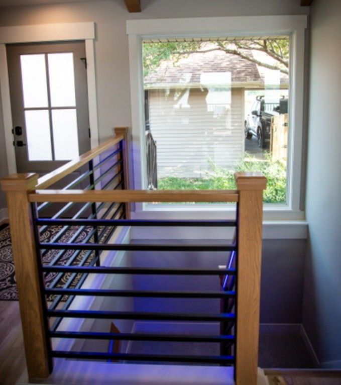 Stairwell landing with wooden railing, window, and blue accent walls overlooking a yard outside