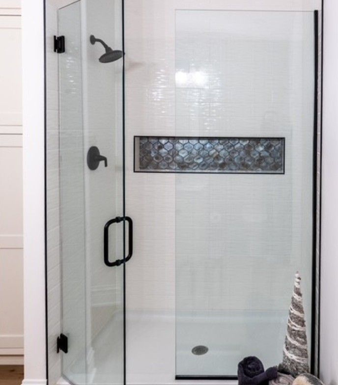 Glass shower enclosure with black hardware and a frosted window panel.