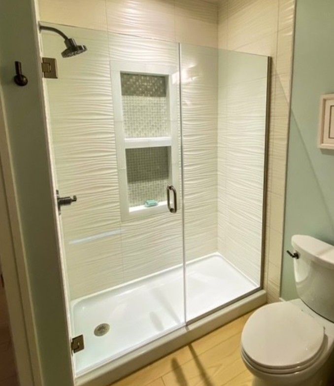 Modern bathroom with glass shower stall and toilet on wood-look floor
