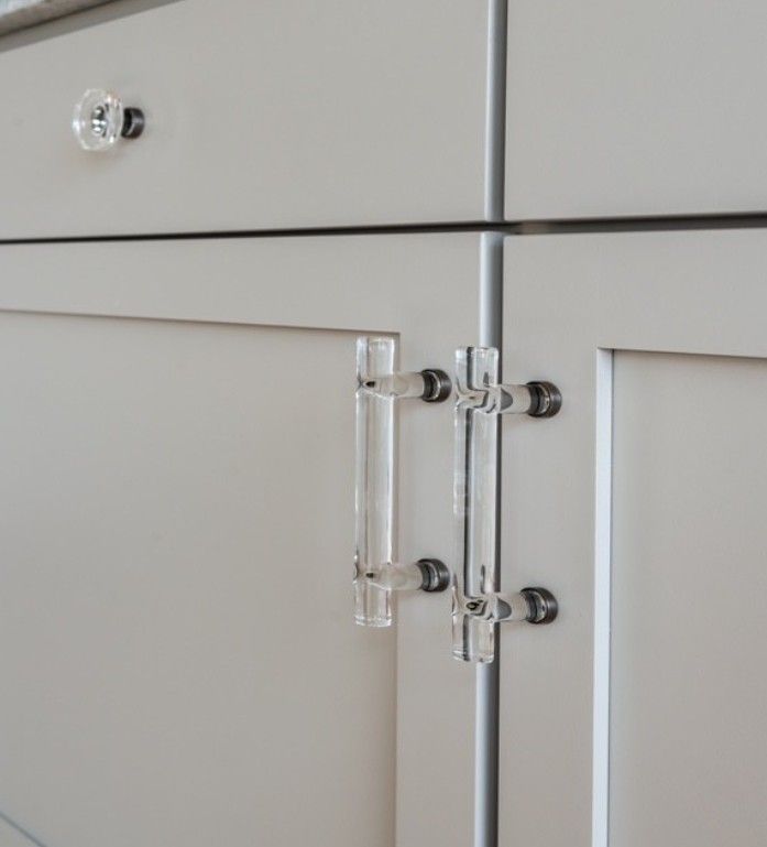 Clear glass cabinet hinge on a light gray cabinet door