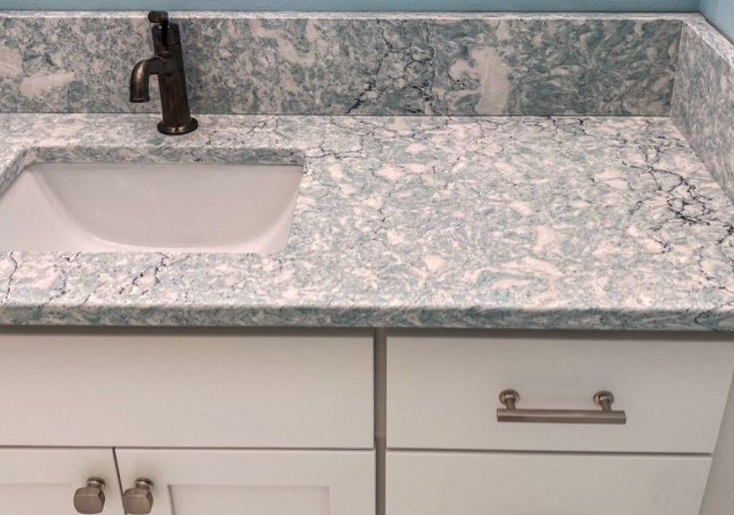 Bathroom vanity with white sink, black faucet, and gray marble countertop and backsplash
