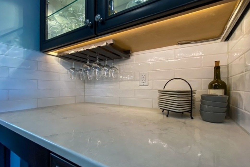 Modern kitchen countertop with white tile backsplash, under-cabinet lighting, and two storage canisters with a bottle