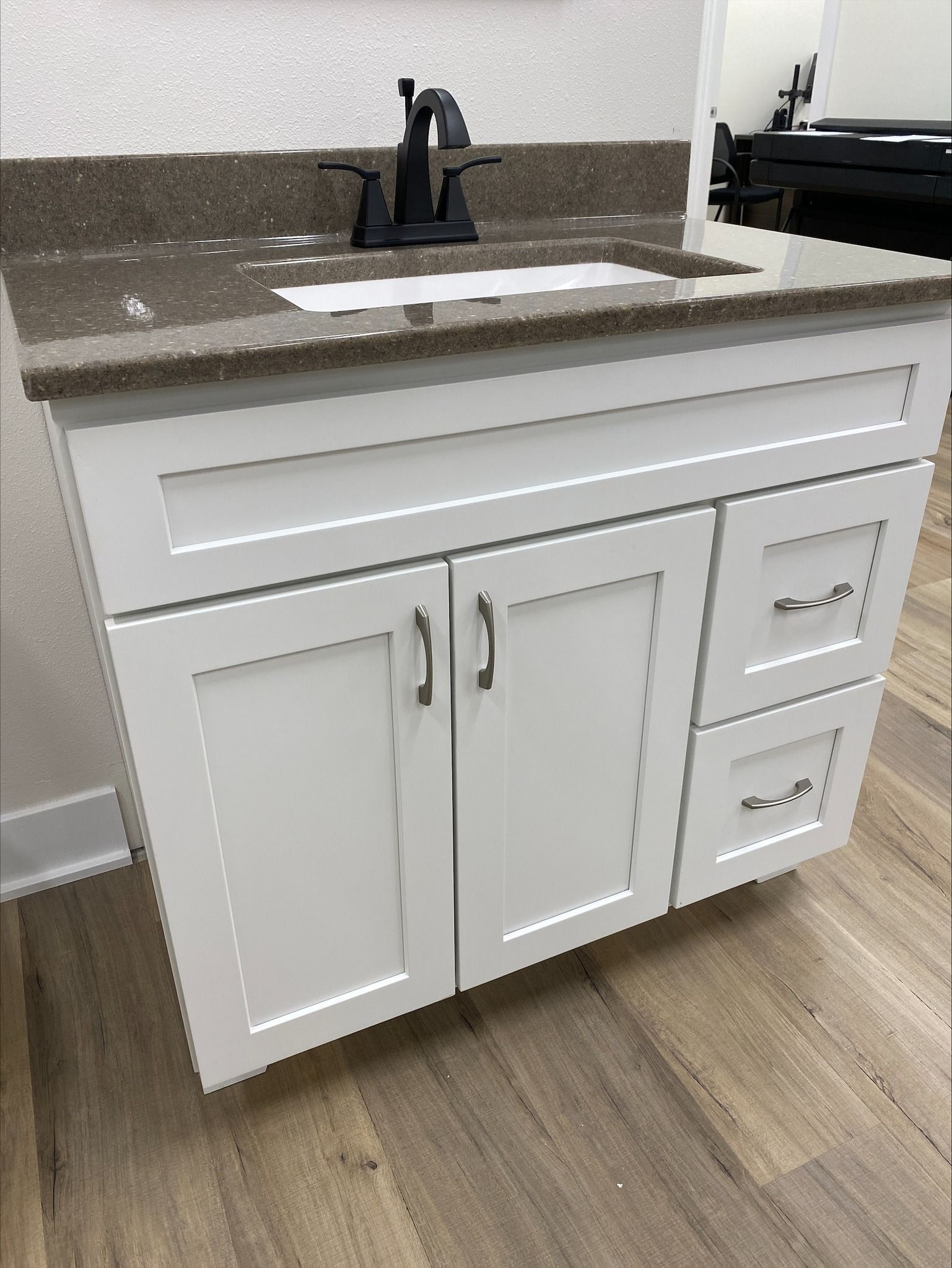 White bathroom vanity with dark countertop and black faucet.