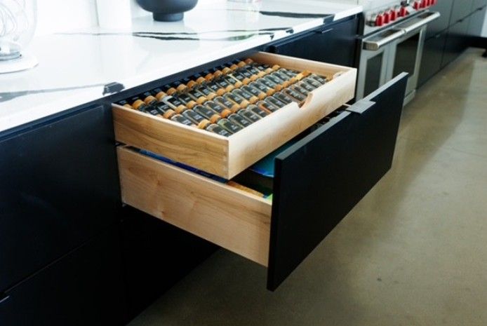 Open drawer with a wooden utensil organizer in a modern kitchen cabinet