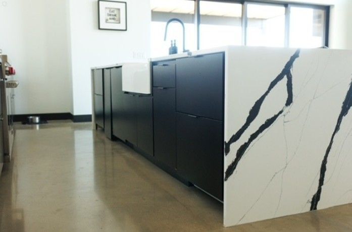 Modern kitchen island with black cabinets and white marble-look panels in a bright room