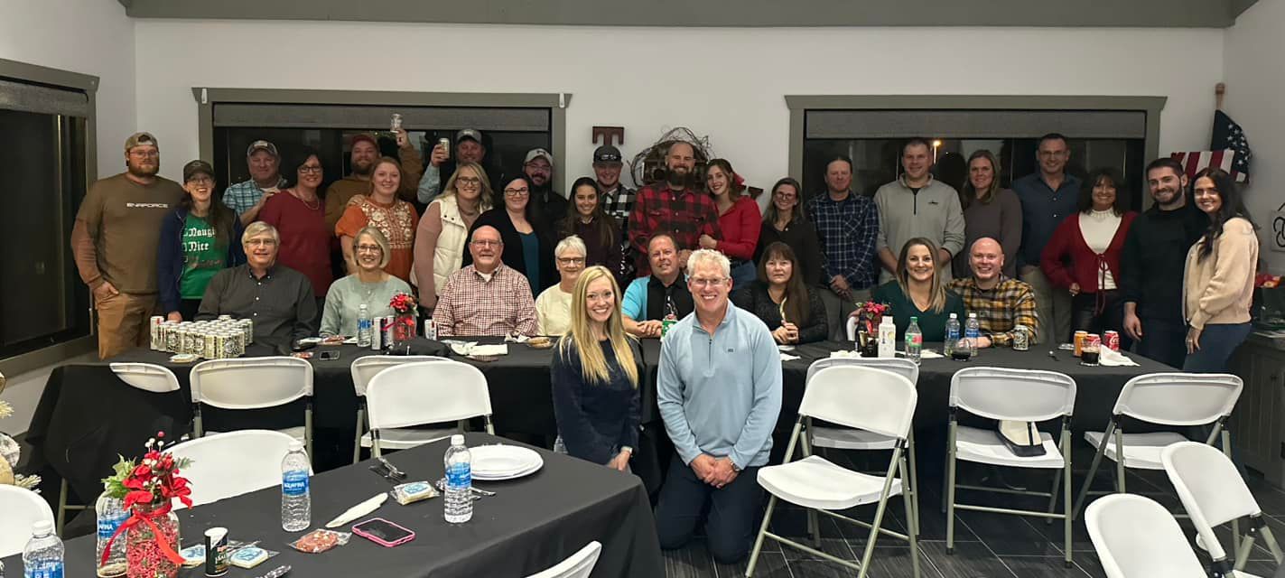 Large group of people gathered indoors at tables and standing behind them.
