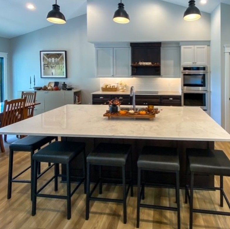 Modern kitchen with large island, black stools, pendant lights, and light blue cabinets