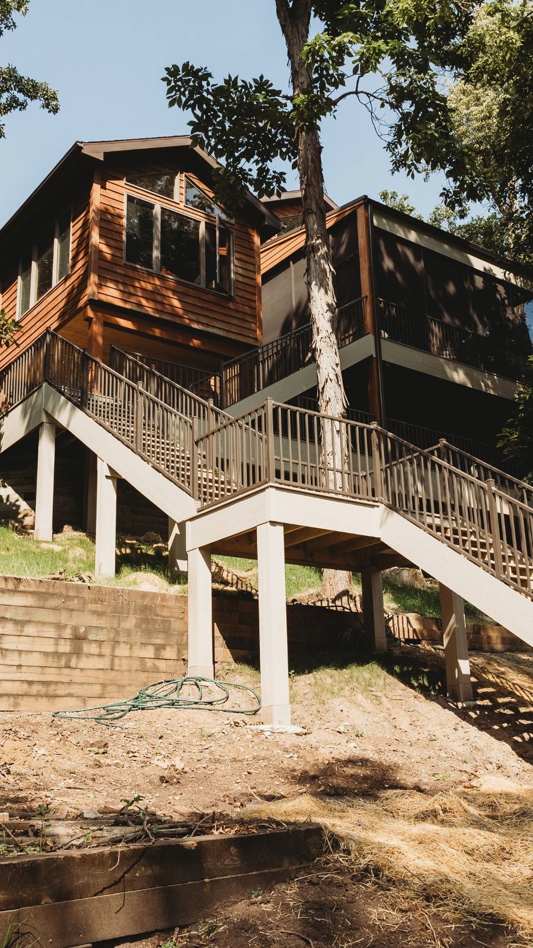 Two-story wood-sided house with multiple decks and staircases leading to the entrance.