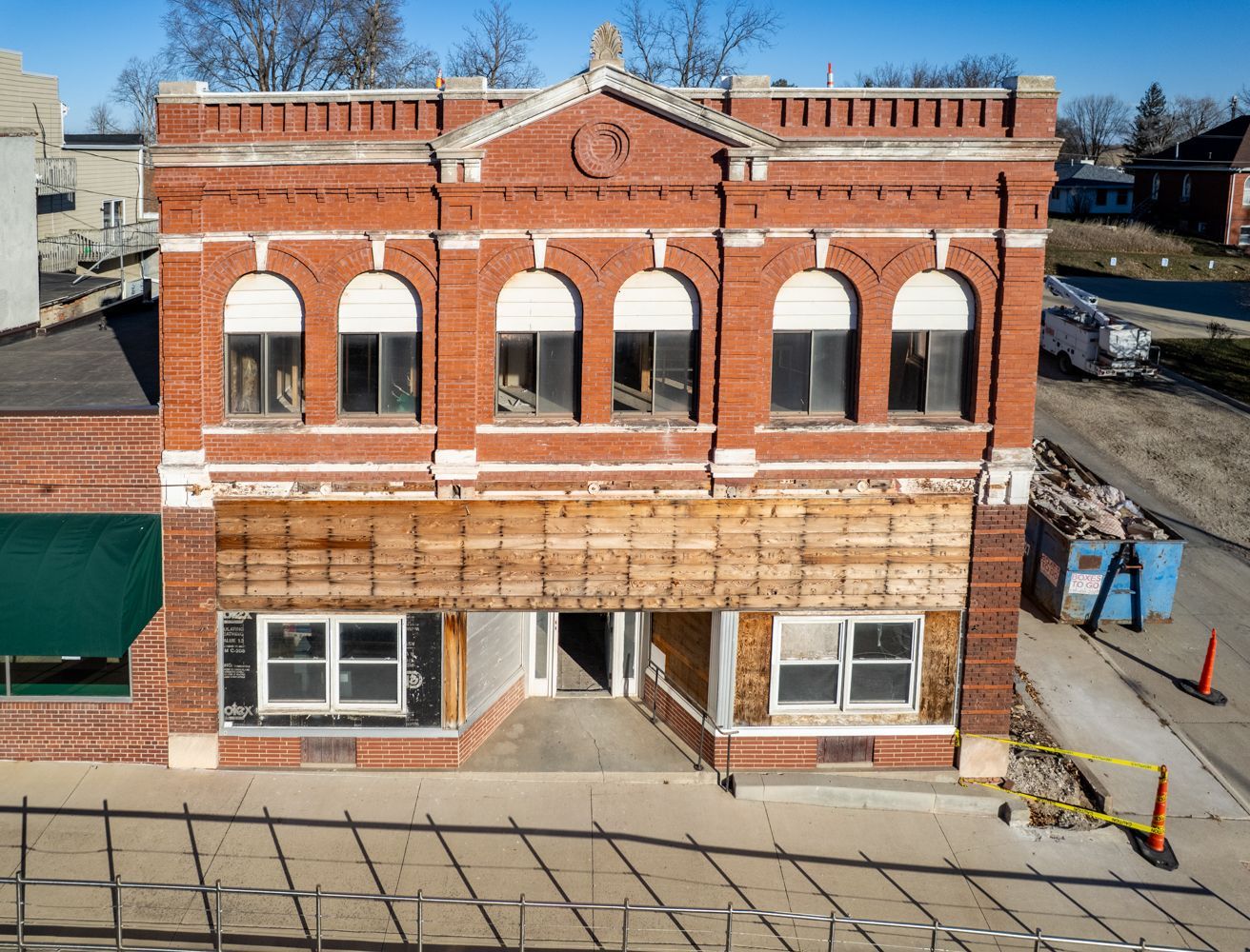 A two-story red brick building with arched upper windows and a ground-floor facade currently under renovation.