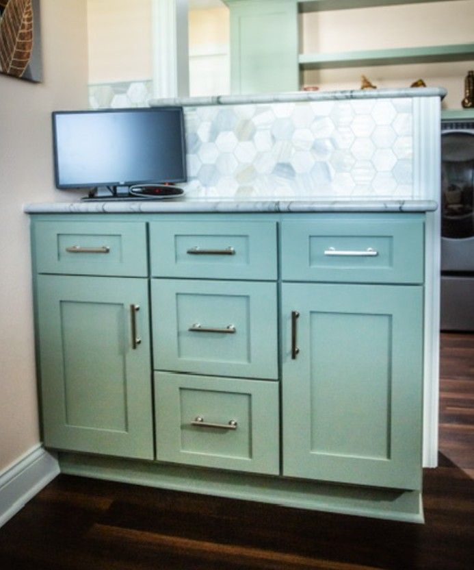 Light mint bathroom vanity with sink, mirror, and small TV on top against dark wood floor