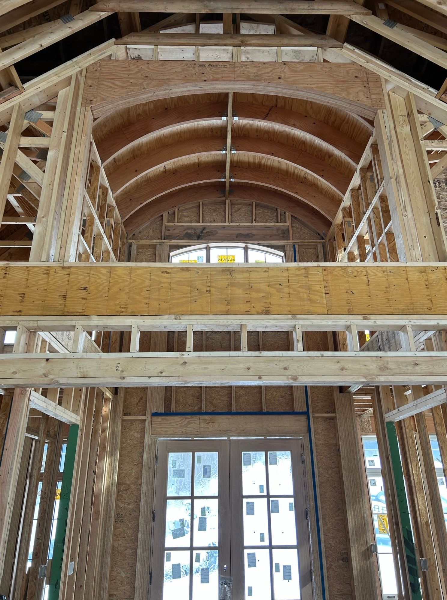 Interior view of a building under construction, showing wooden framing for walls and a curved ceiling.