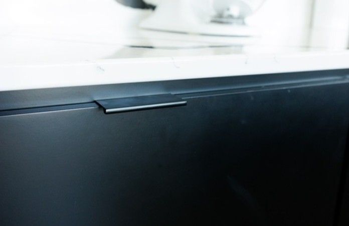 Close-up of a black cabinet drawer with a silver handle beneath a white countertop