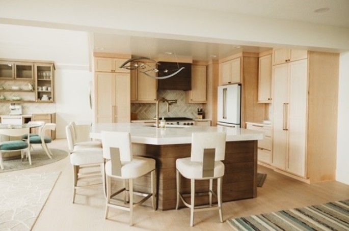 Bright modern kitchen with island, bar stools, light wood cabinets, and adjacent dining area