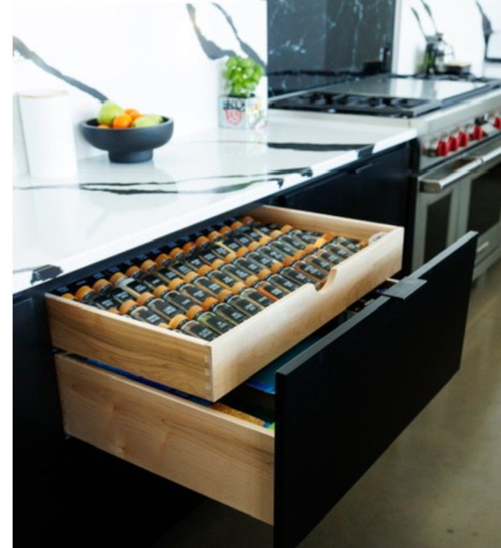 Kitchen drawer organizer with wooden trays and assorted spices near a stovetop