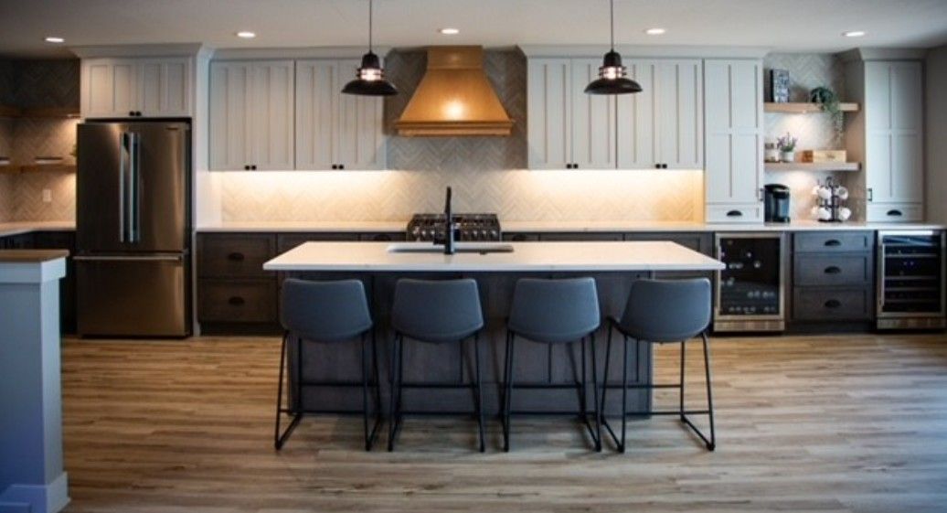 Modern kitchen with island, three stools, pendant lights, and stainless steel appliances