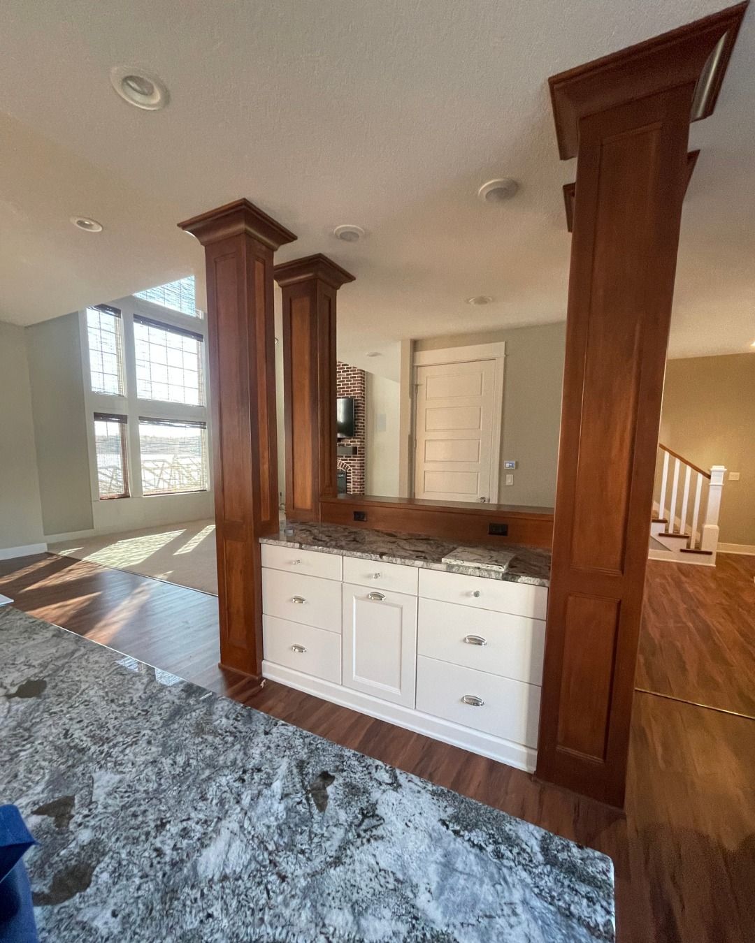 Interior view of a kitchen island with white cabinets, wood columns, and granite countertop.