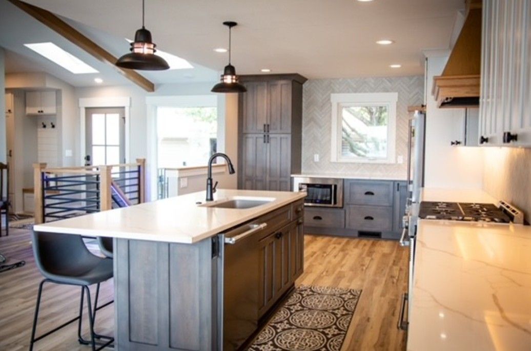 Modern kitchen with large island, pendant lights, gray cabinets, and hardwood floors
