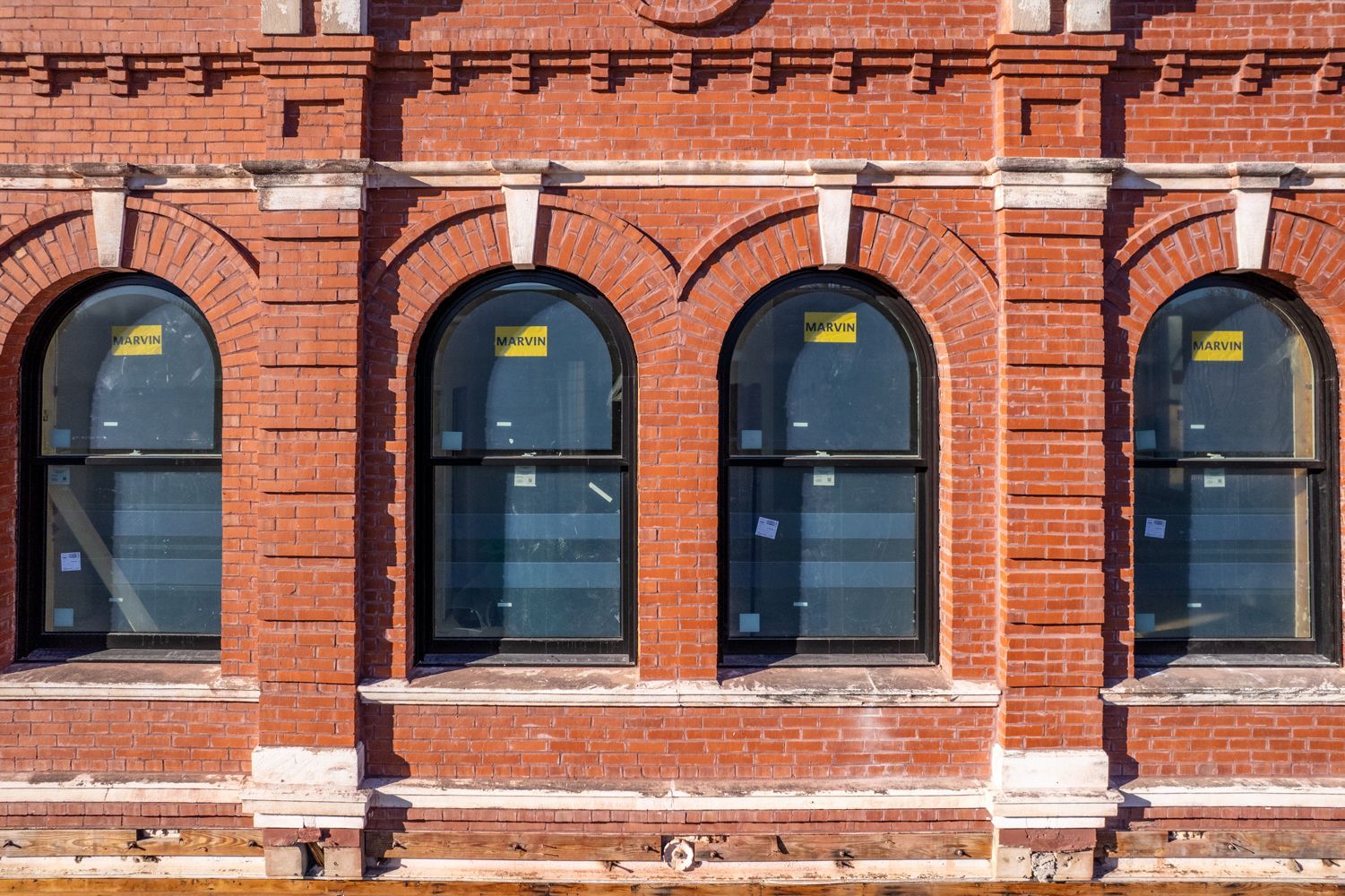Three arched windows in a red brick building with dark frames.