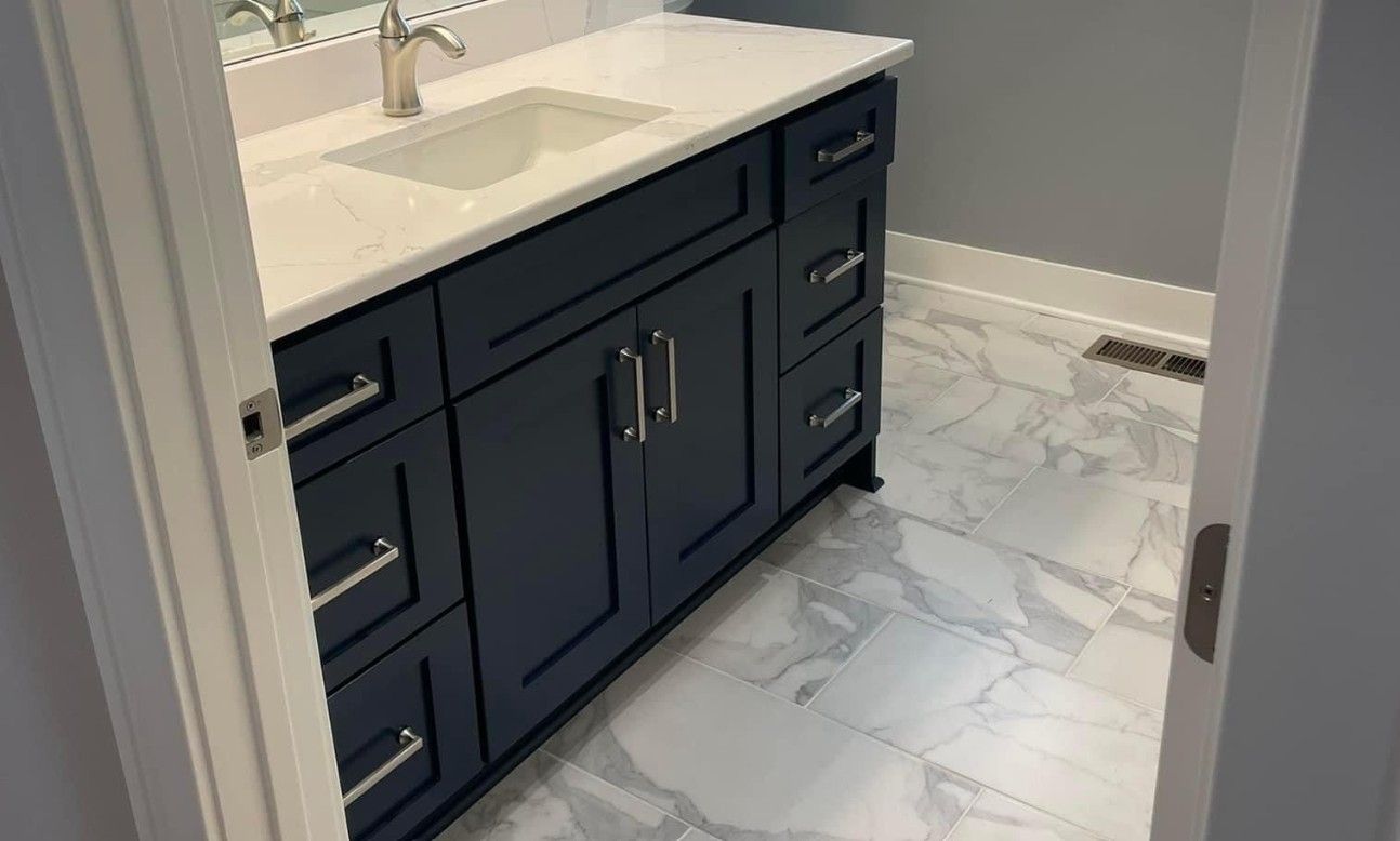 Bathroom vanity with navy cabinets, white countertop, and marble-pattern tile floor
