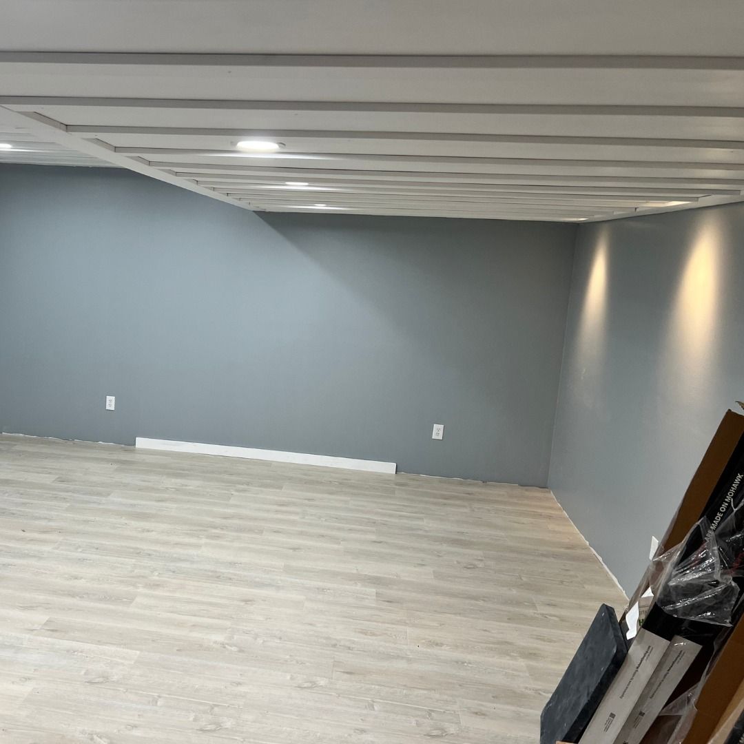 Empty room with gray walls, light wood-look flooring, and a textured white ceiling with recessed lights.