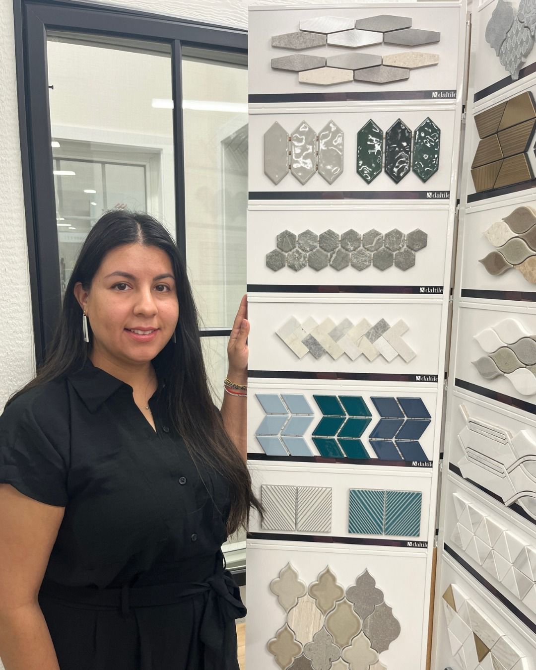 Woman in black dress stands next to tile samples.